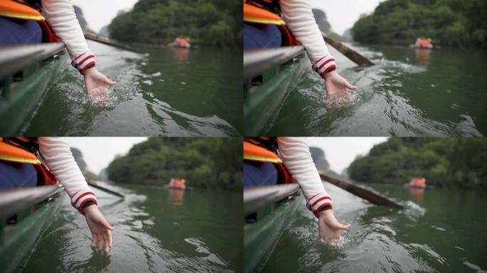 亚洲华裔女孩的手触碰河面