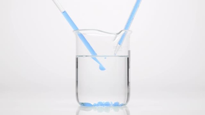 滴管将蓝色的油滴入烧杯的水中，烧杯下沉到底部