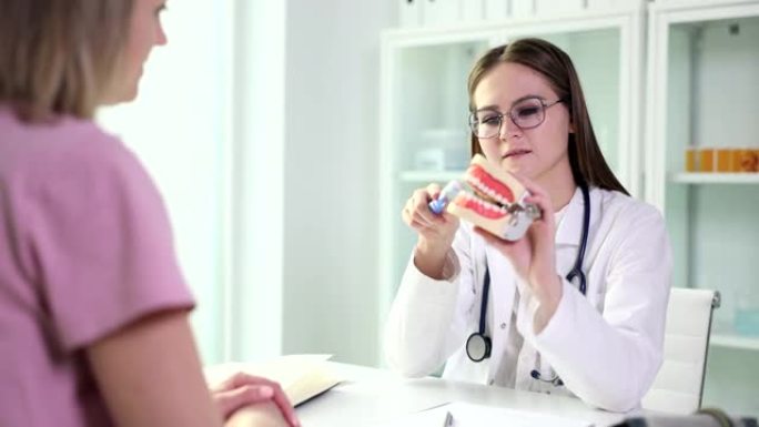 牙医医生展示如何正确刷牙的女性患者的牙齿植入物