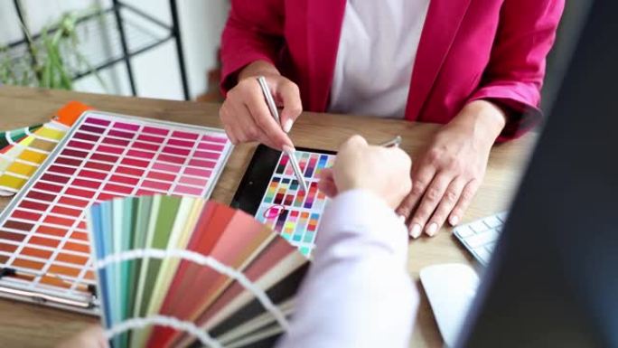设计师帮助客户在平板电脑上从办公室的各种色板中选择颜色