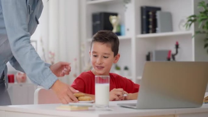妈妈带牛奶和饼干给儿子在家学习，健康的饮食习惯