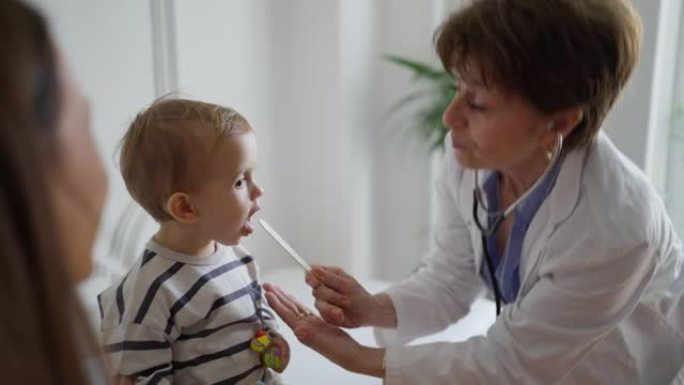 护理儿科医生使用压舌板，同时检查幼儿的喉咙