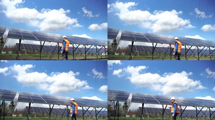 太阳能发电厂的工人在用钻头统一的固定面板上。太阳能电池板附近的工程师