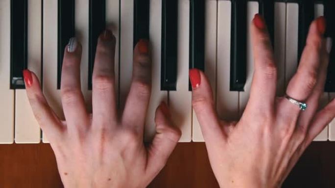 女性手用手指弹奏钢琴键盘特写俯视图