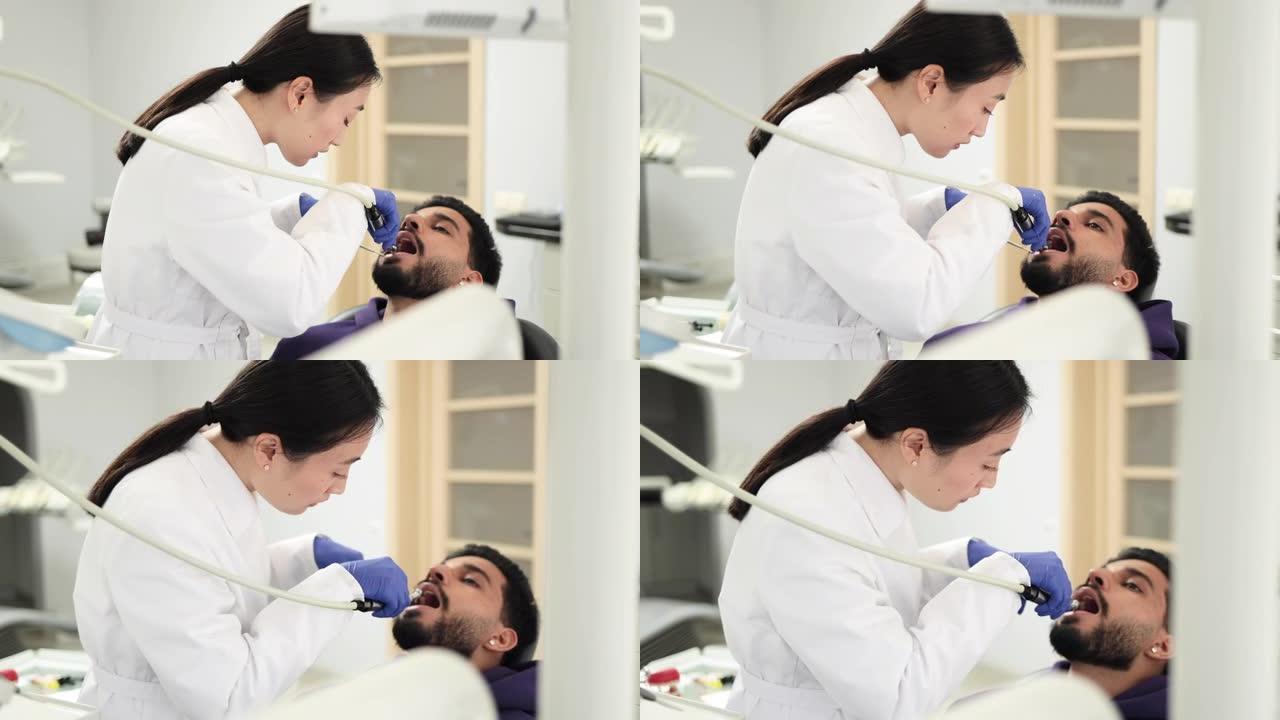 穿着白色制服的漂亮女性亚洲牙医，用钻头进行牙科检查和龋齿治疗