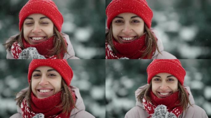 4k慢动作肖像，穿着针织帽和围巾，穿着雪天雪花，在白雪皑皑的冬季公园。女人呼气，用围巾包裹自己。冬天