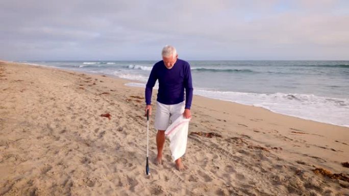成熟的男人在海滩上捡垃圾