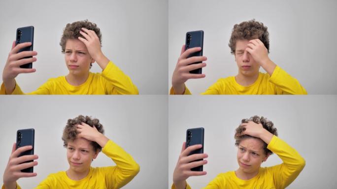 一个年轻男子的肖像，卷发，一边看着电话，一边挤丘疹。人们生活方式概念