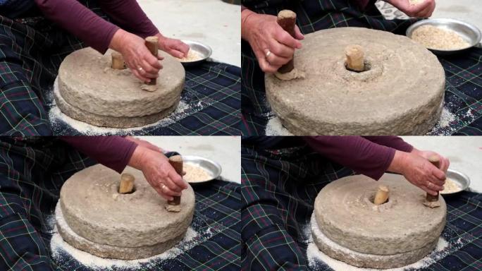 女人正在石磨里手工磨小麦。用传统方法制作面粉。