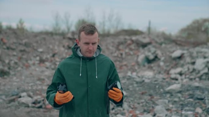 病毒学家男子脱下防护服和呼吸器防毒面具，站在垃圾填埋场污染附近，看着灾难的规模