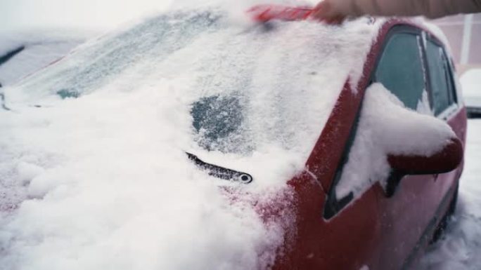 一名男子用刷子清洁一辆冰雪覆盖的汽车。