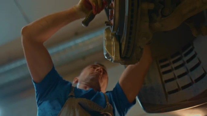 汽车修理工在升降机上的服务站用扳手修理汽车卡钳的肖像。汽车服务。