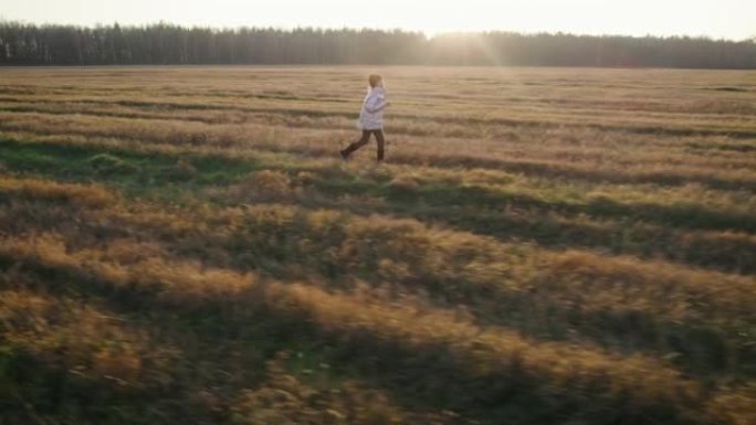 十几岁的女孩在夕阳前跑过田野