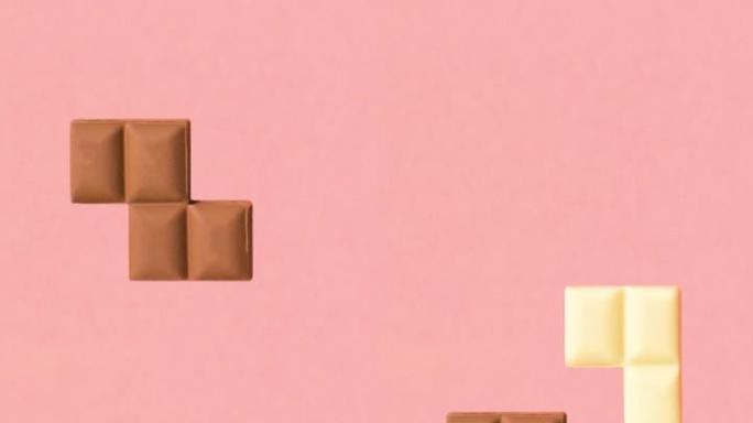 复古游戏俄罗斯方块由柔和的粉红色背景上的黑白巧克力棒制成。创意美食概念动画。怀旧俄罗斯方块或益智游戏