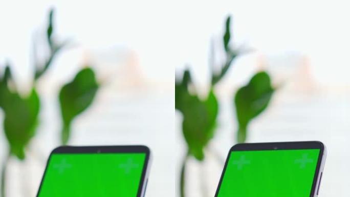 一名男子将手指放在窗户背景下的手机绿屏上。