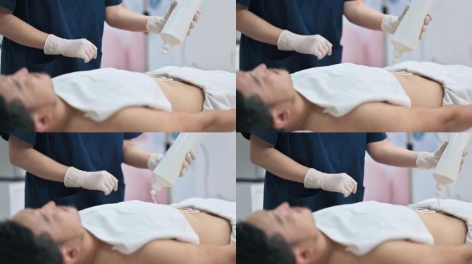 亚洲中国女性美学家在患者腹部涂抹面霜，准备超声腹部脂肪和脂肪团去除。身体护理、水疗护理
