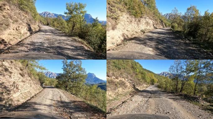 在高而陡峭的山中行驶蜿蜒的道路。阳光明媚的天气里荒芜的道路。岩石山顶。有许多不规则石头的碎石路。尘土