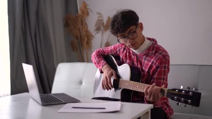 20岁的人在家在线学习吉他。