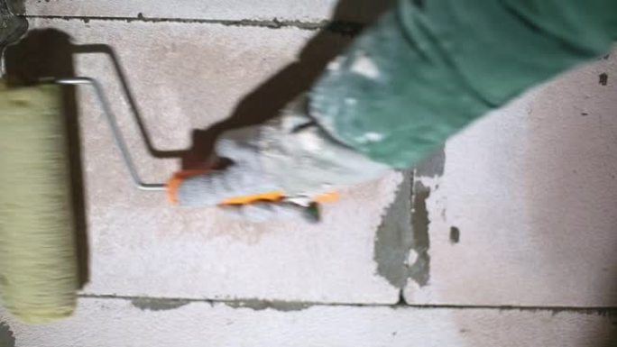 施加液体底漆涂层施工辊准备完成由多孔块制成的房屋的墙壁。油漆底漆，用干燥的建筑混合物处理。修理