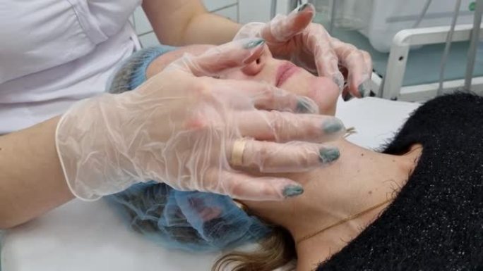 美容院。一位戴着医用手套和防护面罩的美容师，在客户的脸颊上进行九头蛇脱皮手术。侧视图。特写。冠状病毒