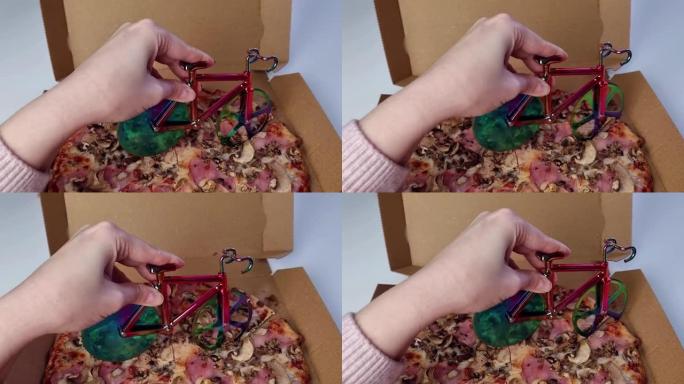 女人在桌子上的纸箱里手工切割美味的比萨饼切片，纸板奶酪上的自行车比萨饼切割刀，快餐送货服务