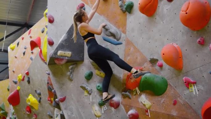 年轻的运动女性在室内攀岩墙上练习