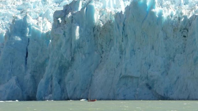 小红船在一个大型潮汐冰川前的惊涛骇浪中航行
