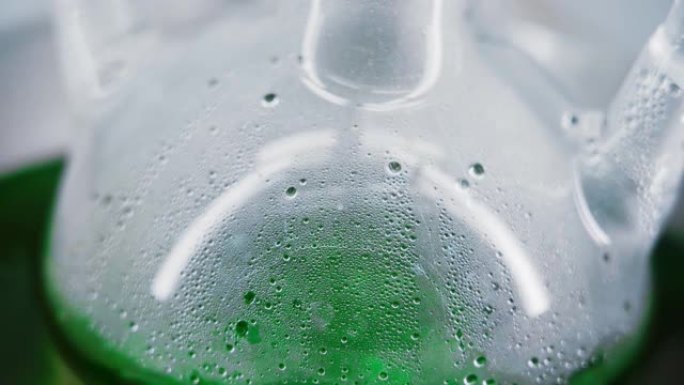 碗里的玻璃烧瓶。绿色液体在烧瓶中沸腾。特写。烧瓶上出现小气泡。实验室中的化学反应。垂直全景。摄像机从