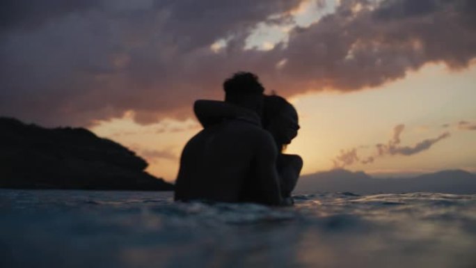 非洲民族浪漫的异性恋夫妇在日落时一起在海里游泳。拥抱