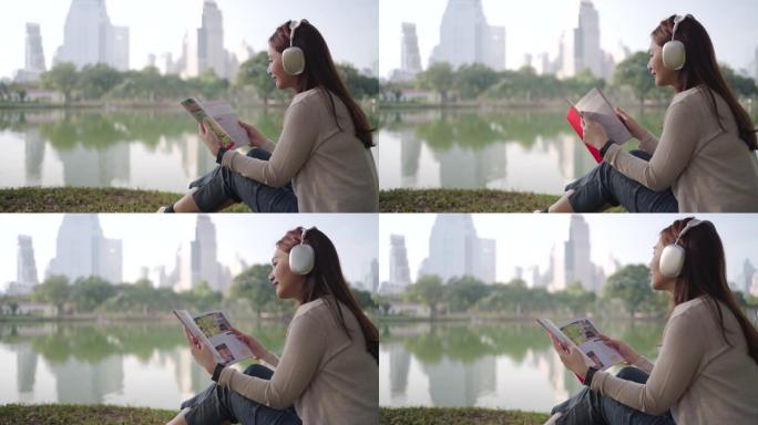 亚洲女性很高兴早上在城市公园听音乐和看书，人们在城市自然环境中放松身心。