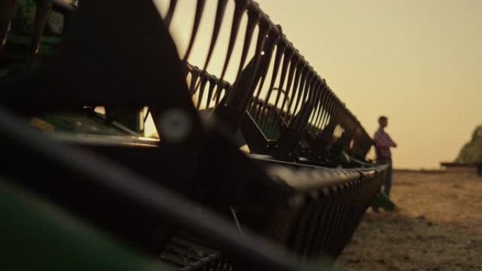 农艺师剪影休息小麦农田精益收割机金色日落。