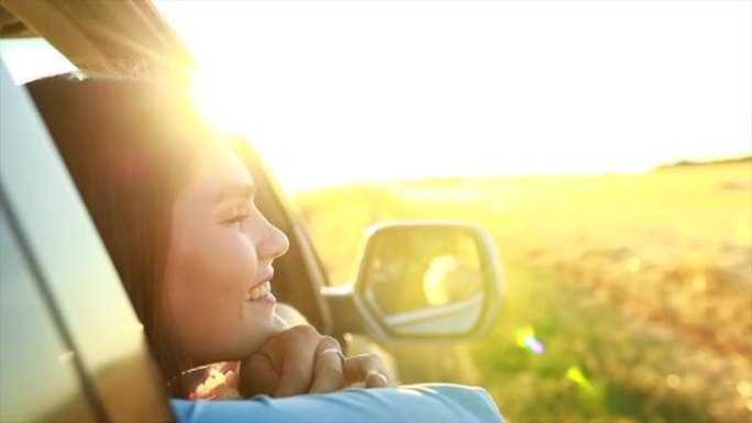 快乐的年轻女子看着窗外金色的夕阳在田野里唱着歌