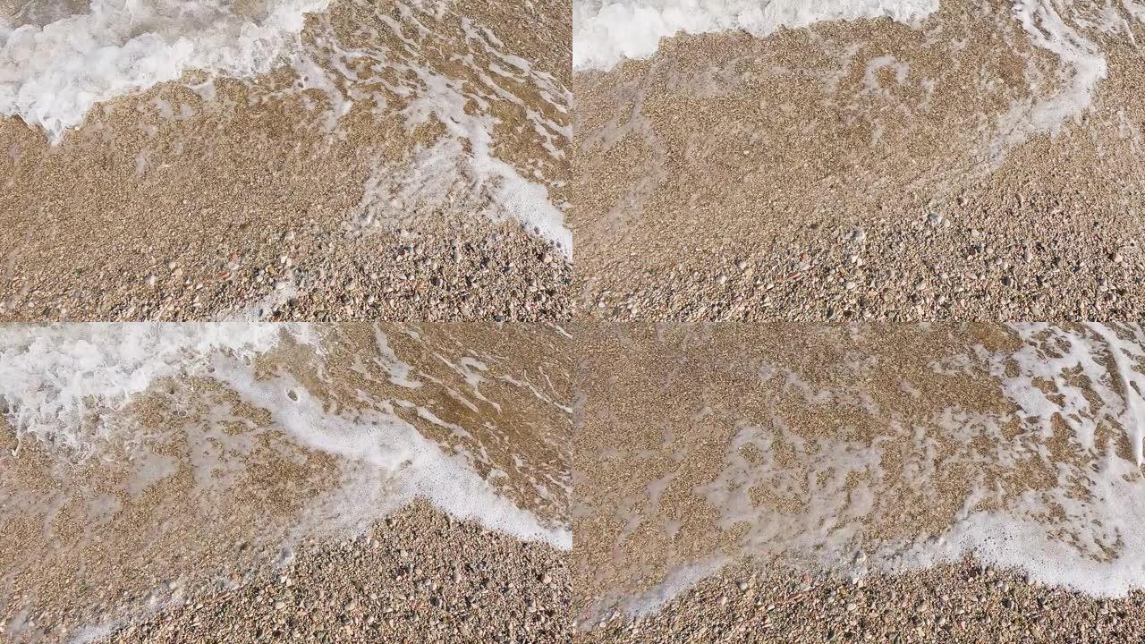 在沙质海岸上冲浪，水以特写镜头滚动到岸上，慢动作
