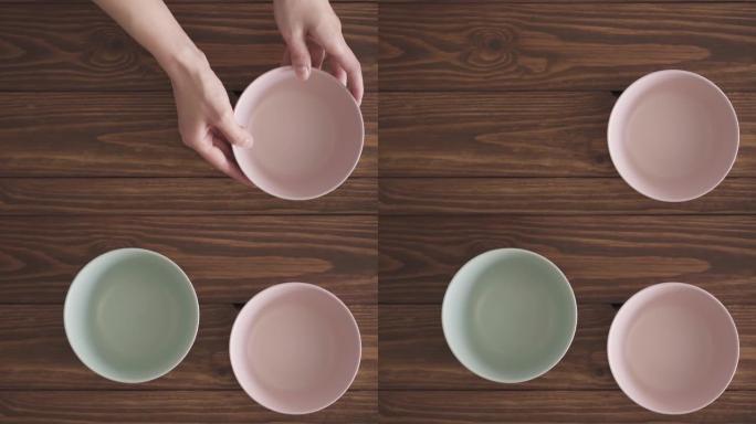 女性双手将三个空碗放在木制纹理桌子上。厨房桌子上的三个碗彼此相邻