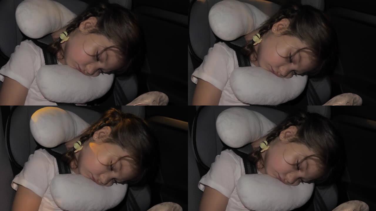 平静平和的女孩睡在汽车后座上。女孩在打盹。小女孩无法忍受漫长的旅程，在舒适的儿童座椅上睡着了，带着路