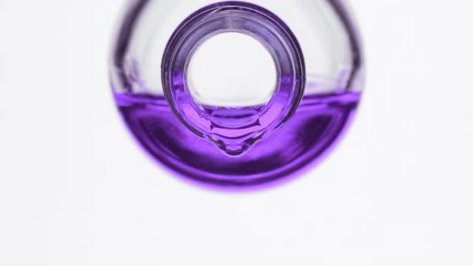 紫色的油从灰色背景上的试剂瓶中滴落