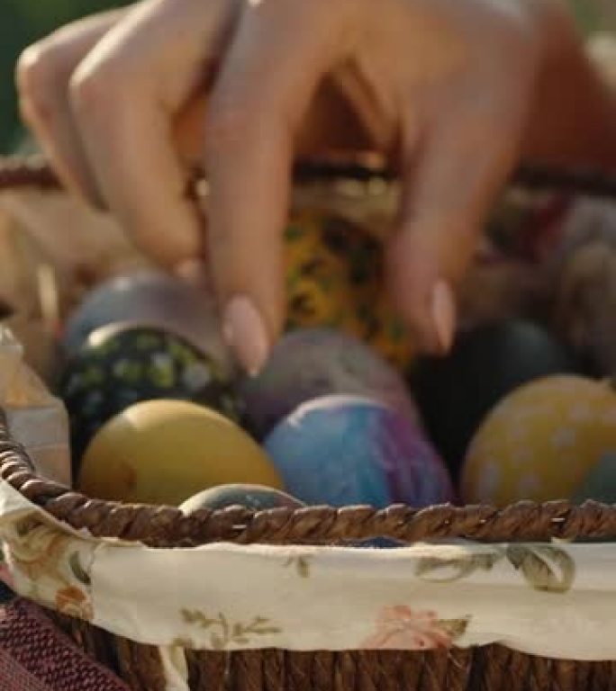 女孩坐在阳光下，拿着一个装有复活节彩蛋的柳条篮，用手旋转着。特写。垂直视频社交媒体