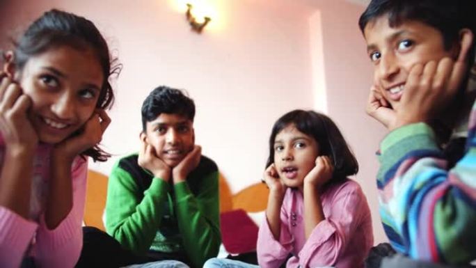 四个南亚孩子坐在卧室里在印度玩耍的低角度镜头