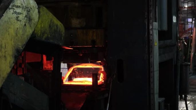 高加索年轻强壮的铁匠在炉子里用明火工作。铁匠锻造热铁车间。钢水铸造后的红色热钢金属坯。连铸机。铁匠和