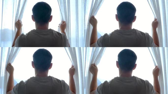 男子站在窗前，打开窗帘后视图。