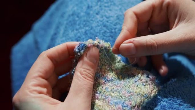 一个女人用自己的双手为孩子做袜子。