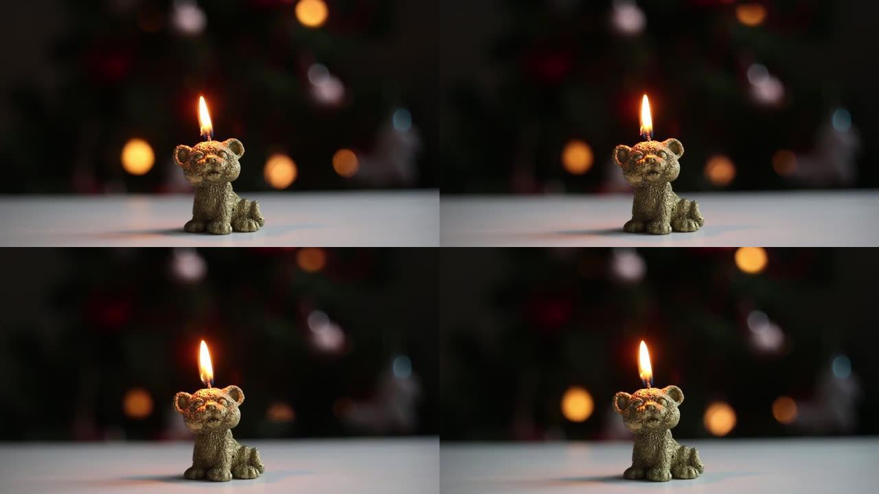 在闪烁的圣诞节花环的背景下燃烧着老虎的蜡烛雕像。