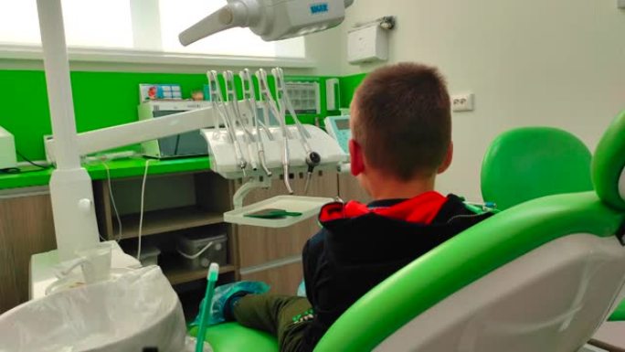 男孩坐在牙医椅上，竖起大拇指。儿童牙科和医学概念