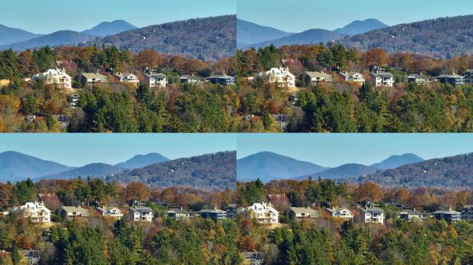 从北卡罗来纳州郊区黄色秋天树木之间的山顶高处的昂贵住宅的上方观看。美国梦homes作为美国郊区房地产