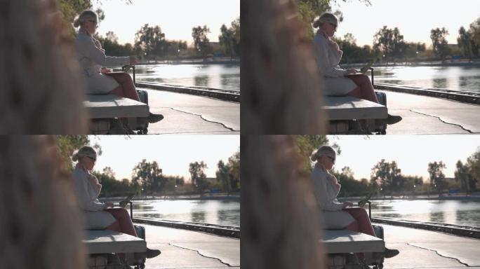 成熟的女人在水边附近的长凳上使用笔记本电脑