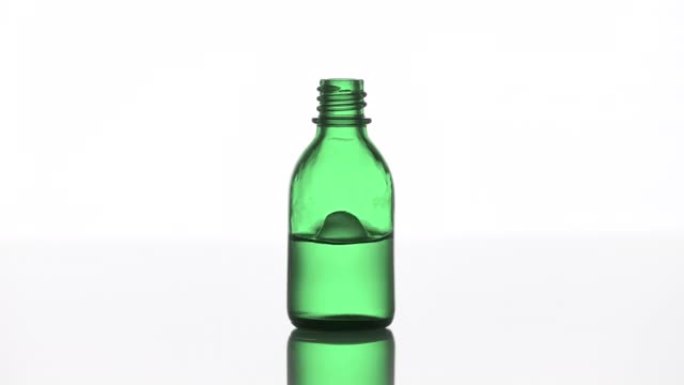 掉落到绿色医疗瓶中，液体产生飞溅