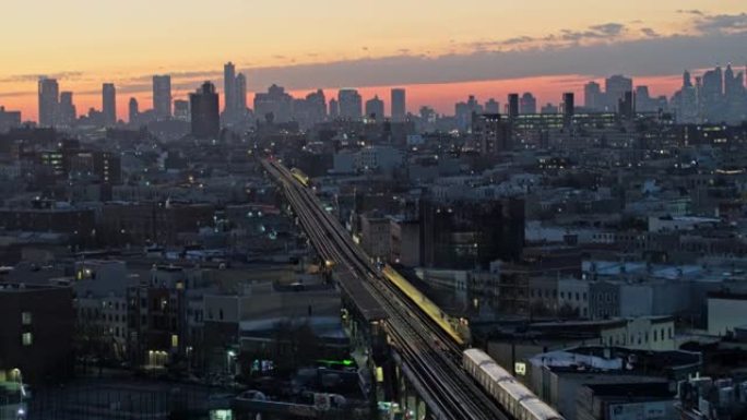日落时分，布鲁克林市中心在布什威克 (Bushwick) 居民区上空的鸟瞰图，一列火车到达前景中的翻