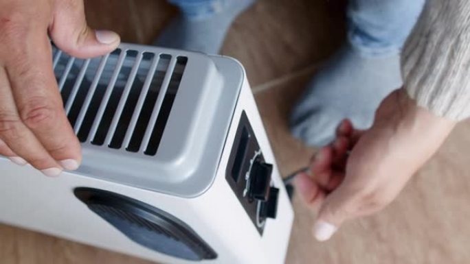 男人正在尝试在家中加热和调节电散热器的温度