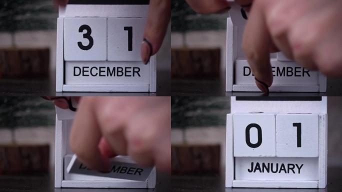 女人的手将白色木制日历上的日期更改为新年