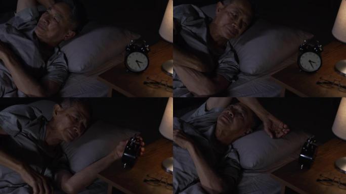 抑郁的亚洲老人失眠睡不着觉。